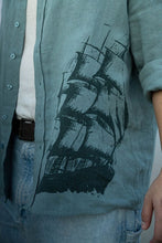 Load image into Gallery viewer, Light blue shirt with a black ship design on a plain background
